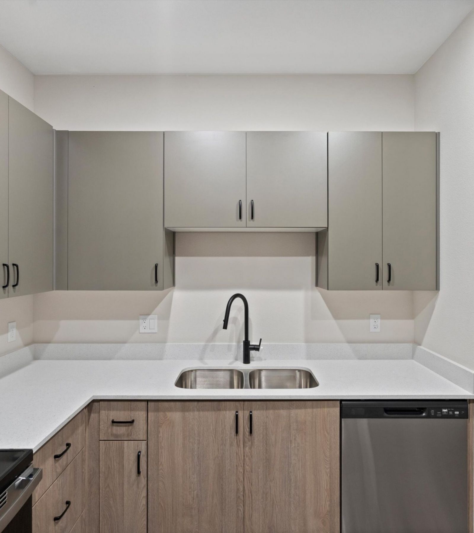 Modern kitchen with gray cabinets, stainless steel appliances, and a double sink with a black faucet.
