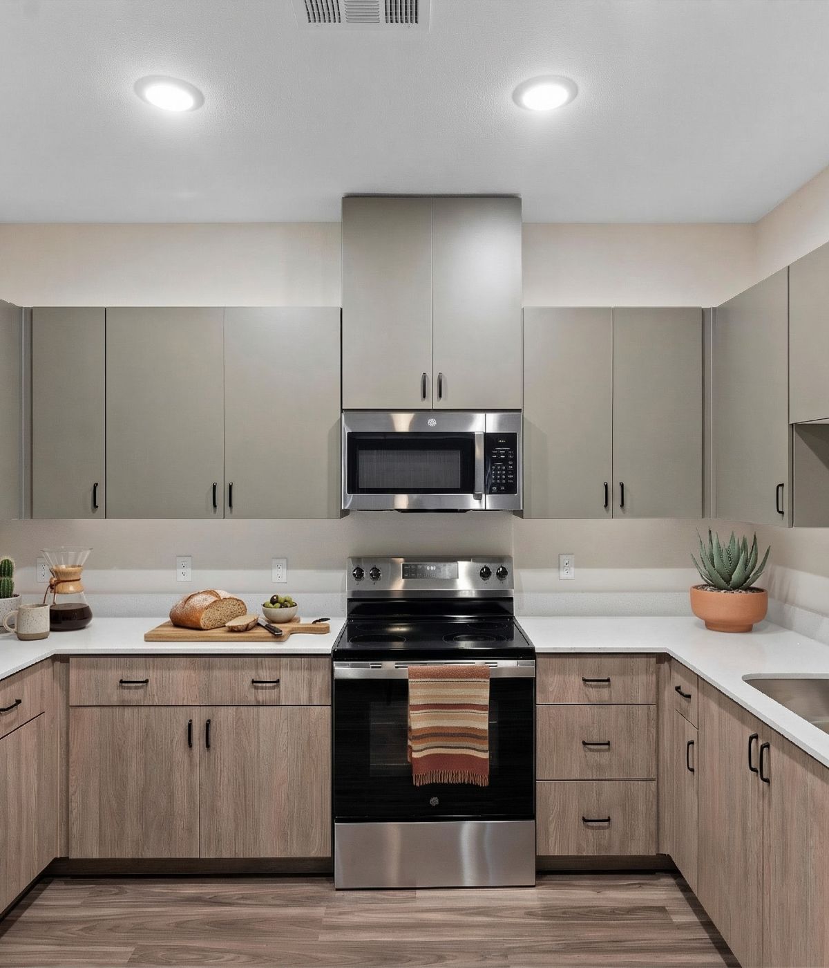 Modern kitchen with stainless steel appliances, neutral cabinets, and a striped towel on the oven handle.