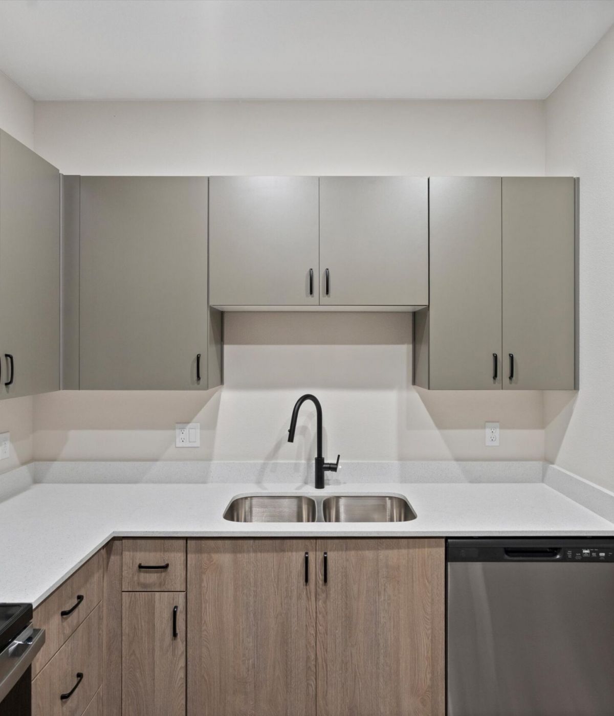 Modern kitchen with gray cabinets, stainless steel appliances, and a double sink with a black faucet.