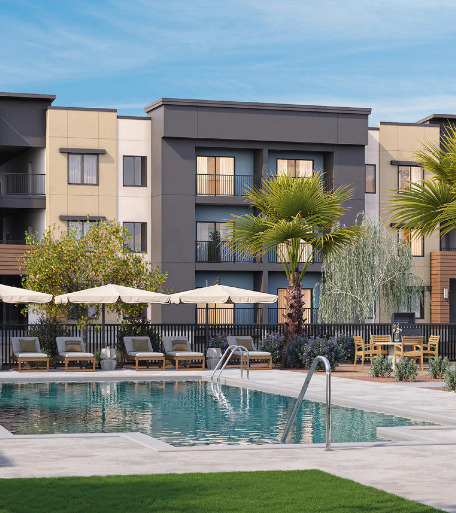 Modern apartment complex with a pool, lounge chairs, umbrellas, and palm trees on a sunny day.