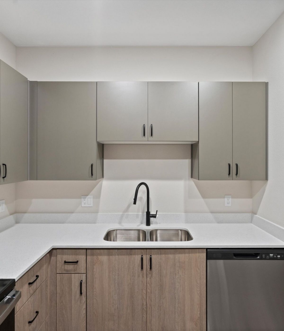 Modern kitchen with gray cabinets, stainless steel appliances, and a double sink with a black faucet.